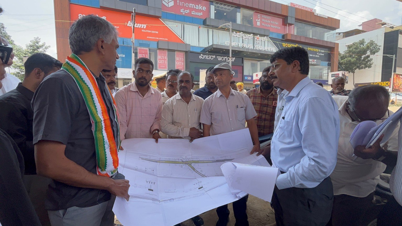 Krishna Byre Gowda and officials examining road plans.