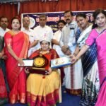 Felicitation ceremony at the Akhila Karnataka Brahmana Mahasabha with a seated honouree holding an award
