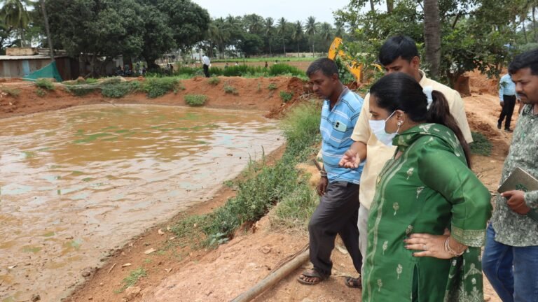 Officials inspect a catfish pond during the Hoskote operation