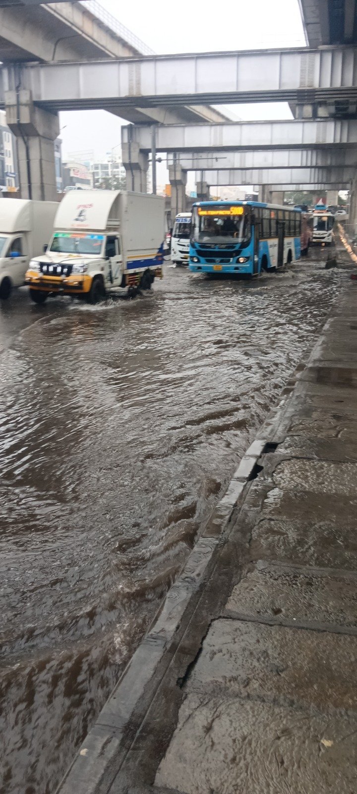 Vehicles move through waterlogging near Kasturi Nagar down-ramp toward Tin Factory in Bengaluru