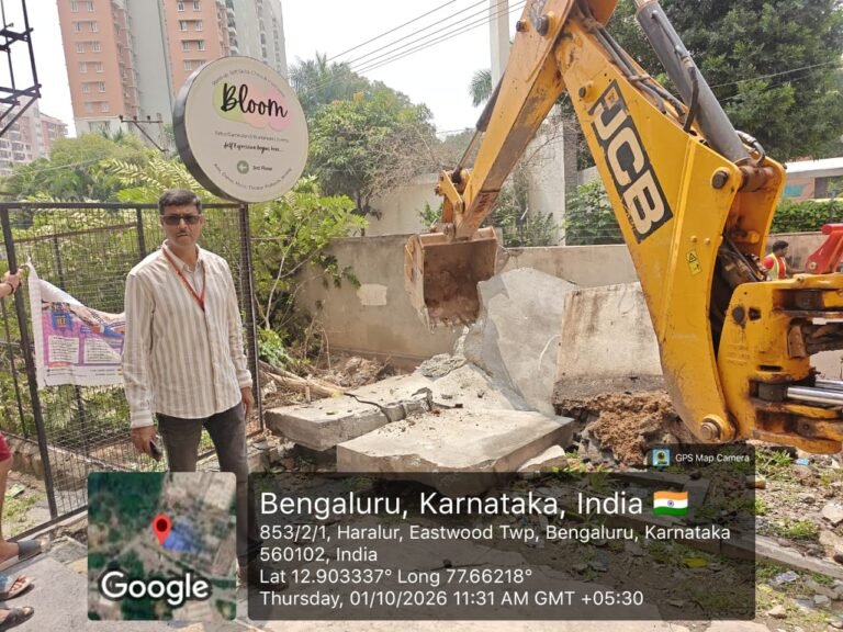 Excavator removes a compound wall during Haralur stormwater-drain encroachment clearance