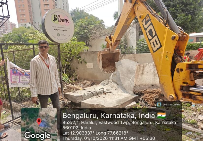 Excavator removes a compound wall during Haralur stormwater-drain encroachment clearance