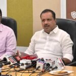 UT Khader speaking at a media briefing with microphones in front of him
