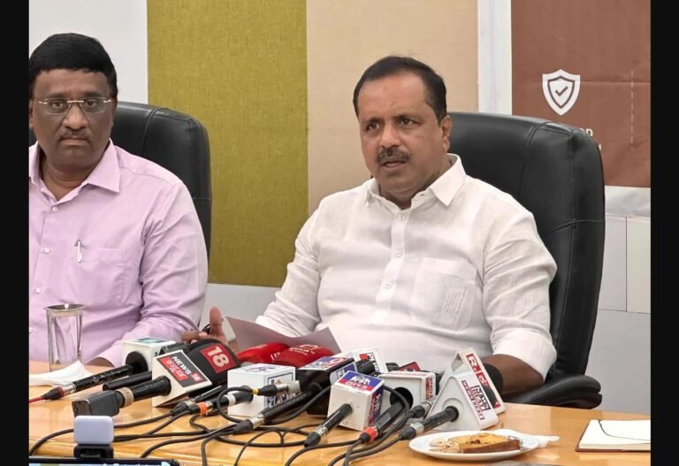 UT Khader speaking at a media briefing with microphones in front of him
