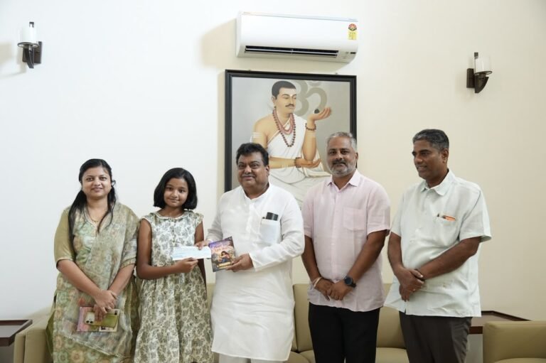 Young author Shivani Biradar and M.B. Patil hold a cheque and her book Magic Tales for Little Hearts
