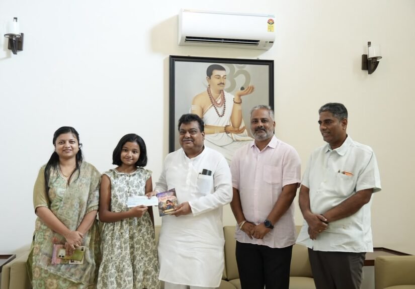 Young author Shivani Biradar and M.B. Patil hold a cheque and her book Magic Tales for Little Hearts