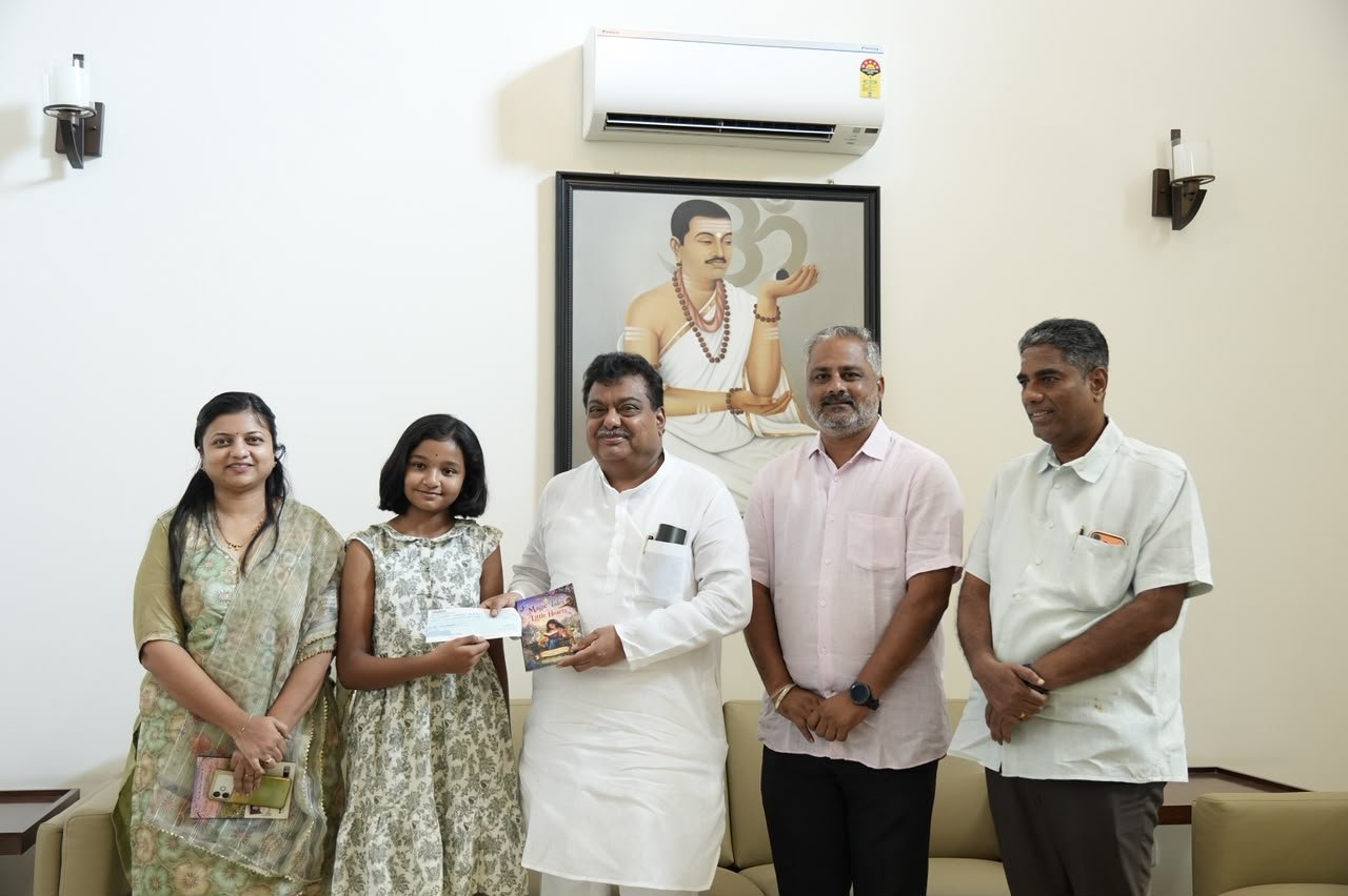 Young author Shivani Biradar and M.B. Patil hold a cheque and her book Magic Tales for Little Hearts