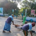 Sanitation workers clean a public area beside a Bengaluru lake