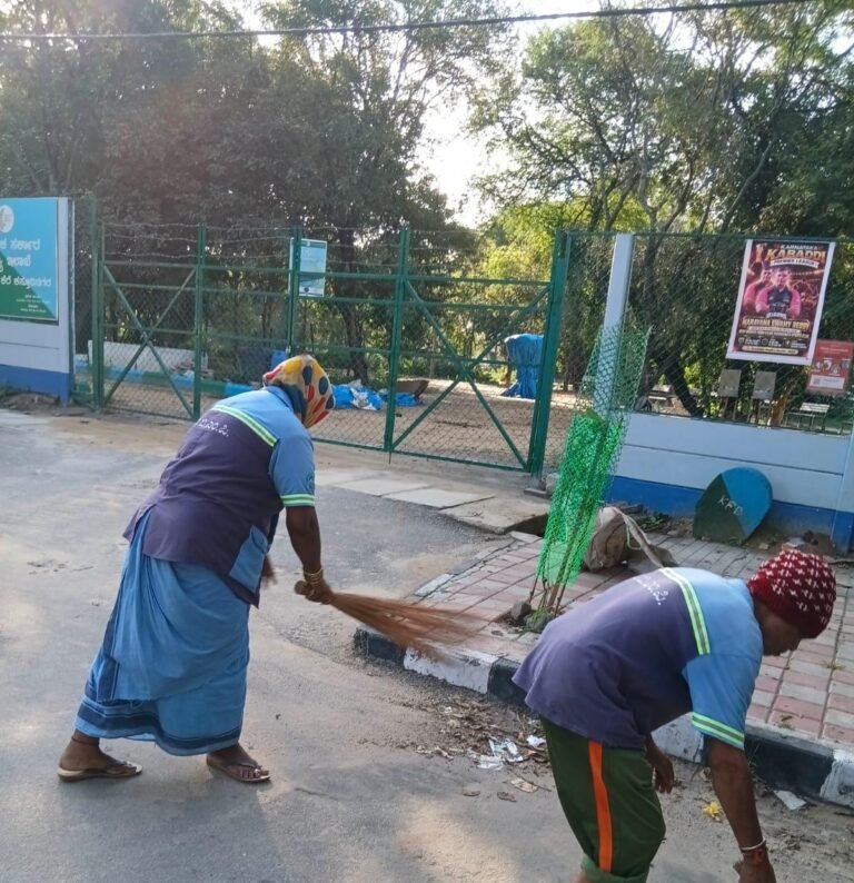Sanitation workers clean a public area beside a Bengaluru lake