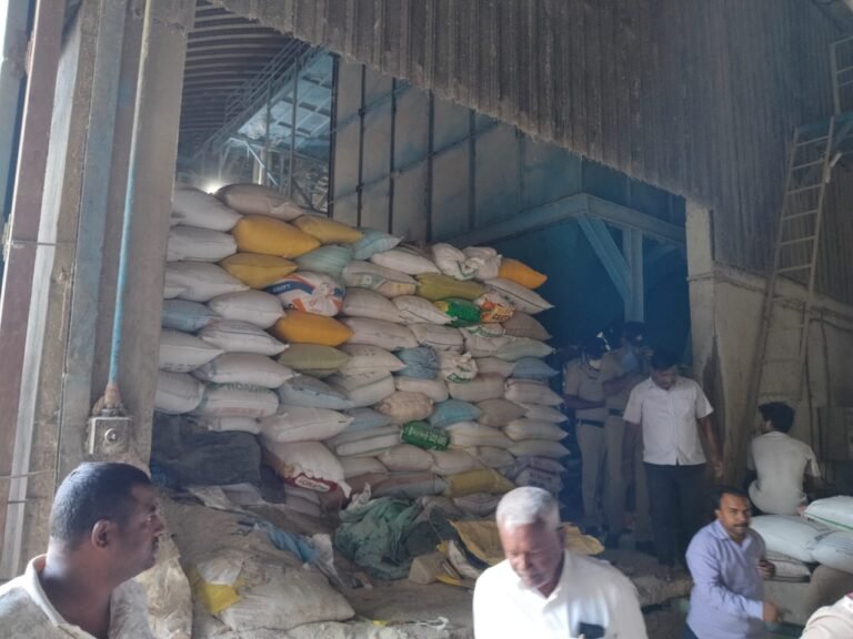 Officials beside stacked grain sacks inside a storage premises