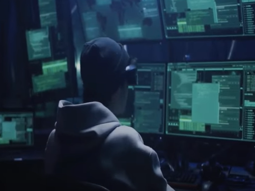 Representational file image of a person facing computer screens for a bank alerts advisory